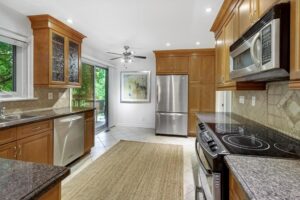 Kitchen with granite countertops, wood cabinetry, stainless steel appliances, and tile backsplash at 12 Vistaview Blvd.