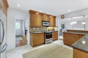 Kitchen with granite countertops, wood cabinetry, stainless steel appliances, and tile backsplash at 12 Vistaview Blvd.