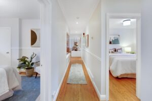 Upstairs hallway at 12 Vistaview Blvd connecting the bedrooms, decorated with artwork and hardwood flooring.