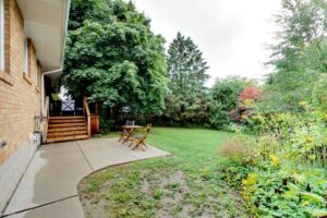 Concrete patio off the deck off the kitchen at 12 Vistaview Blvd overlooking a mature tree and backyard greenspace.
