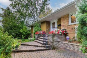 Front exterior of 12 Vistaview Blvd with brick facade, landscaped gardens, and a stone walkway leading to the entrance.