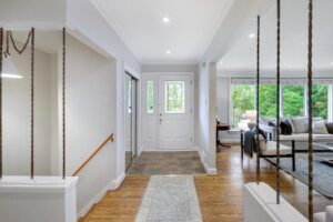 Bright entryway at 12 Vistaview Blvd featuring a white front door with glass insets and a view into the living room.