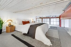 Loft space with low ceilings set a sleeping nook for guests with a queen sized bed.