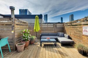 Rooftop deck lounge area with sectional seating and potted plants.
