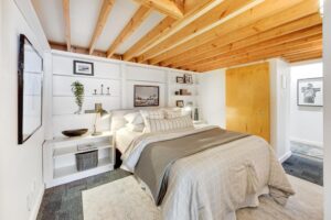 Primary bedroom with built-in shelving flanking a queen sized bed. Exposed wood beams cross the ceiling.