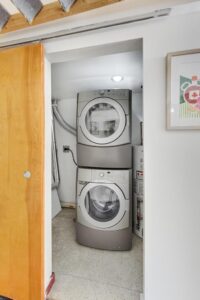 Stacked washer and dryer in a closet with a barn door.