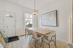 Bright dining area at 21 Blackburn St with a large front window, modern pendant light, and a light wood table with six upholstered chairs.